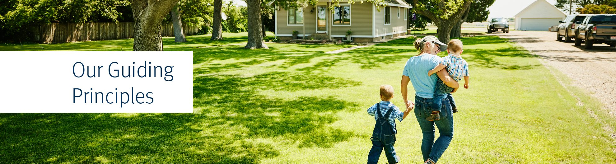 Wide shot rear view of grandmother walking with grandsons through front yard of home